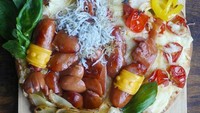 Sekilas tampilan pizza buatan Etoni ini tampak penuh topping sosis. Namun kalau diperhatikan, bentuk sosisnya menyerupai karakter King Triton, ayah dari Ariel. Foto: Instagram Etoni Mama