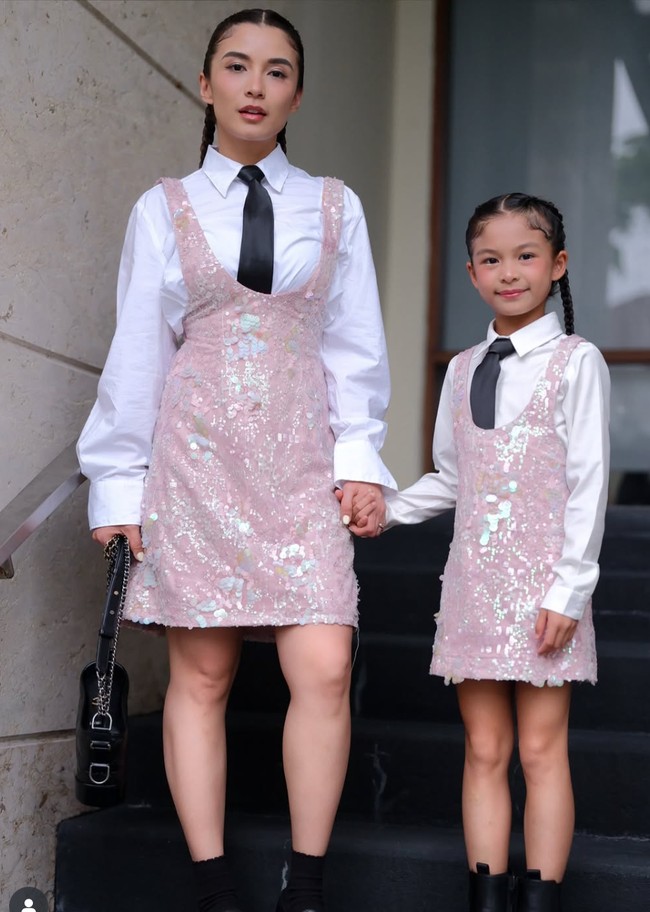 Chelsea Olivia tampil kembar bareng sang putri, Nastusha. Keduanya mengenakan kemeja putih yang dipadukan dengan dasi hitam dan dress sequin warna baby pink. Keduanya juga memilih gaya rambut kepang dua yang sama. Foto: Instagram