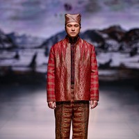 Peragaan karya Auguste Soesastro di panggung Dewi Fashion Knights 2025 ditutup dengan penampilan aktor Nicholas Saputra. Berlenggang di catwalk, ia memeragakan setelan merah dengan jas tak berkancing yang elegan, dipadu celana panjang songket yang terasa mewah berkat jahitan benang emas. (Foto: Dok. Jakarta Fashion Week)