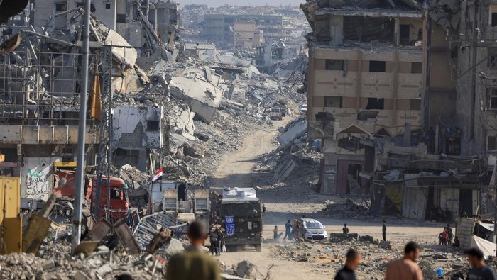 A machinery operates next to a Red Cross vehicle at an area within the so-called 