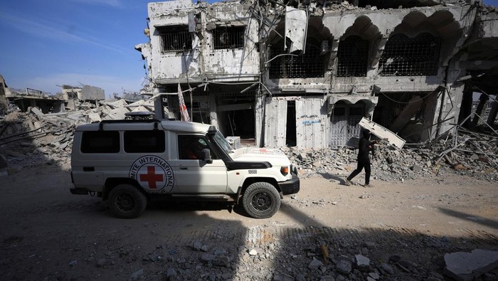 A machinery operates next to a Red Cross vehicle at an area within the so-called 
