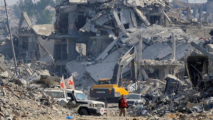 A machinery operates next to a Red Cross vehicle at an area within the so-called 