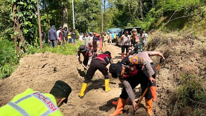 Petugas melakukan pembersihan material longsor yang menutup akses jalan