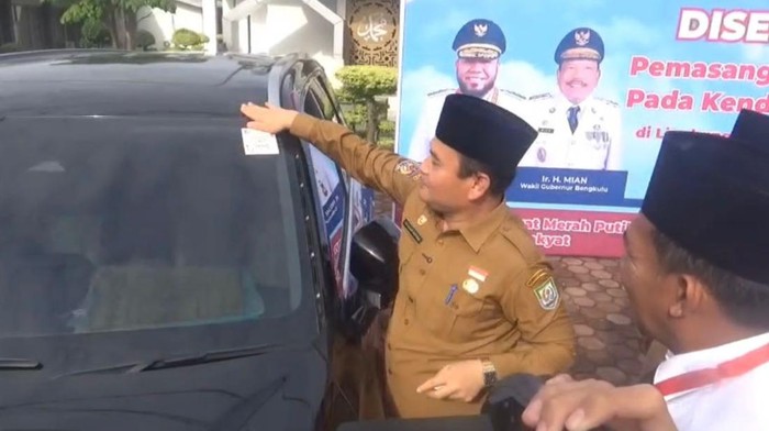 Sekda Bengkulu saat memasang QR Code di kendaraan dinas.