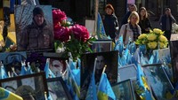 Di Lapangan Kemerdekaan (Maidan Nezalezhnosti), simbol perjuangan rakyat Ukraina, sejumlah warga tampak berjalan melewati tugu peringatan darurat yang dipenuhi bendera nasional dengan nama-nama prajurit yang gugur di medan perang. REUTERS/Gleb Garanich