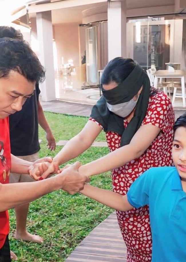 Masih mengenakan daster, Ashanty yang matanya ditutup kain tampak digandeng oleh suaminya, Anang Hermansyah, dan putra mereka, Arsy. Foto: Instagram/@ashanty_ash