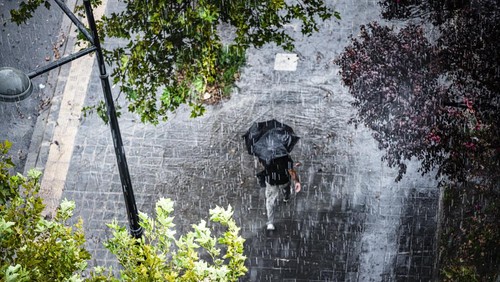 Aerial view of a man with umbrella walking under heavy rain. High resolution 42Mp outdoors digital capture taken with SONY A7rII and Canon EF 70-200mm f/2.8L IS II USM Telephoto Zoom Lens