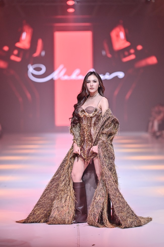 Aura seksi Mahalini sukses terpancar dalam balutan minidress dengan bodice korset yang dihiasi detail payet emas nan glamor. Menambah kesan dramatis, coat berpotongan jubah penuh bulu yang ikut membungkus tubuhnya. (Foto: Dok. JFW)
