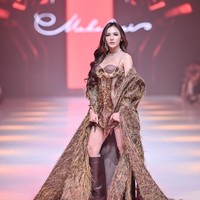 Aura seksi Mahalini sukses terpancar dalam balutan minidress dengan bodice korset yang dihiasi detail payet emas nan glamor. Menambah kesan dramatis, coat berpotongan jubah penuh bulu yang ikut membungkus tubuhnya. (Foto: Dok. JFW)
