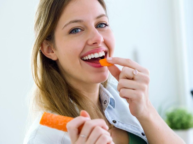 Ilustrasi wanita makan wortel.
