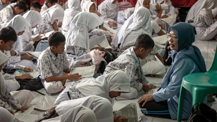 Seorang guru SDN 1 Sayung mengajar muridnya di Kantor Balai Desa Sayung, Kecamatan Sayung, Demak, Jawa Tengah, Rabu (5/11/2025). Kegiatan belajar mengajar di sekolah itu terpaksa dipindahkan sementara ke Kantor Balai Desa Sayung dan dua rumah warga, karena pada Senin (3/11) banjir akibat curah hujan tinggi yang terakumulasi sejak Rabu (10/10) menggenangi seluruh ruang kelas sehingga menyebabkan aktivitas kegiatan belajar mengajar terganggu. ANTARA FOTO/Aji Styawan/tom.