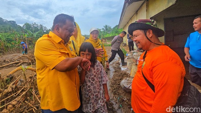 Ketua DPRD Kabupaten Sukabumi, Budi Azhar Mutawali, berbincang dengan Kanaya, pelajar kelas 3 SDN Cikahuripan, di lokasi banjir bandang, Rabu (5/11/2025). Kanaya kehilangan seluruh seragam dan perlengkapan sekolah akibat bencana tersebut.