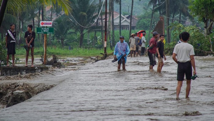 Warga melintasi lahar hujan Gunung Semeru yang meluap dari Sungai Regoyo di Desa Gondoruso, Kecamatan Pasirian, Lumajang, Jawa Timur, Rabu (5/11/2025). Lahar hujan yang tercatat mencapai amplitudo 38 milimeter tersebut menyebabkan tanggul sepanjang 150 meter jebol sehingga memutus akses jalan menuju permukiman tiga dusun dan sekitar 300 kepala keluarga terisolasi. ANTARA FOTO/Irfan Sumanjaya
