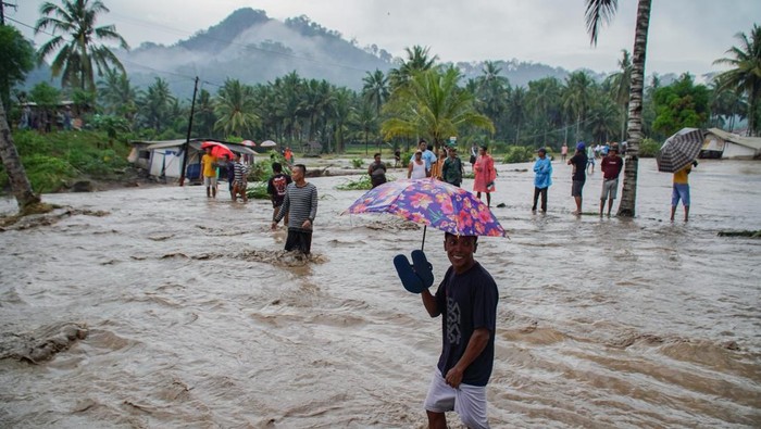 Warga melintasi lahar hujan Gunung Semeru yang meluap dari Sungai Regoyo di Desa Gondoruso, Kecamatan Pasirian, Lumajang, Jawa Timur, Rabu (5/11/2025). Lahar hujan yang tercatat mencapai amplitudo 38 milimeter tersebut menyebabkan tanggul sepanjang 150 meter jebol sehingga memutus akses jalan menuju permukiman tiga dusun dan sekitar 300 kepala keluarga terisolasi. ANTARA FOTO/Irfan Sumanjaya