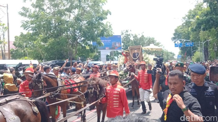 Masyarakat menyambut melihat kereta jenazah PB XIII di Jalan Slamet Riyadi, Rabu (5/11/2025).