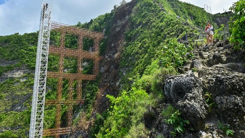 Wisatawan melihat pemandangan di samping bangunan lift kaca di tebing kawasan wisata Pantai Kelingking, Nusa Penida, Klungkung, Bali, Rabu (5/11/2025). Proyek pembangunan lift kaca setinggi 182 meter tersebut dihentikan sementara oleh Panitia Khusus Tata Ruang, Aset, dan Perizinan (Pansus TRAP) DPRD Bali karena dinilai melanggar Undang-Undang Nomor 26 Tahun 2007 tentang Penataan Ruang. ANTARA FOTO/Fikri Yusuf