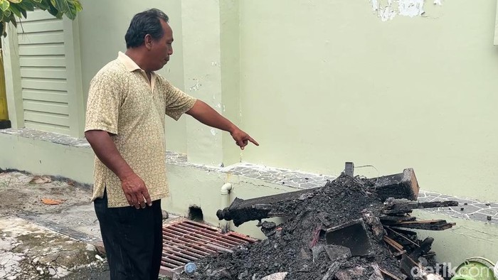 Sekuriti komplek bernama Halomoan Panjaitan saat menunjuk bekas material yang terbakar. (Finta Rahyuni/detikSumut)