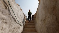 Seorang anak Palestina berjalan memasuki Gua. Beberapa warga Palestina berlindung di gua-gua bawah tanah yang digali bertahun-tahun lalu sebagai tempat perlindungan sementara. Foto: REUTERS/Mussa Qawasma