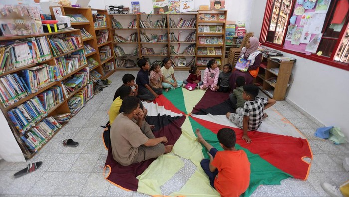 A member of the Palestinian Red Crescent Society reads a story to children as part of mental support activities at the organization’s centre, in Khan Younis in the southern Gaza Strip, October 30, 2025. REUTERS/Ramadan Abed