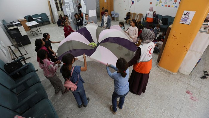 A member of the Palestinian Red Crescent Society reads a story to children as part of mental support activities at the organization’s centre, in Khan Younis in the southern Gaza Strip, October 30, 2025. REUTERS/Ramadan Abed