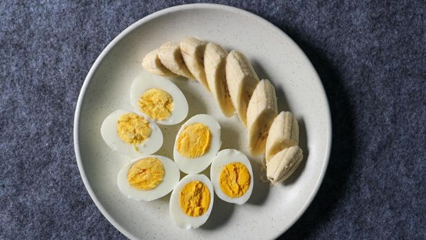 Healthy food. Boiled eggs and sliced bananas on a plate.