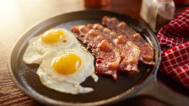 fried bacon and eggs in iron skillet shot with selective focus