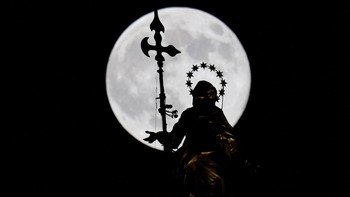 Supermoon “Beaver Moon” terbenam di belakang patung Madonnina di puncak Katedral Duomo, Milan, Italia, Rabu (5/11/2025). Keindahan supermoon menjadi momen langit langka yang terekam di berbagai belahan dunia. REUTERS/Fabrizio Bensch