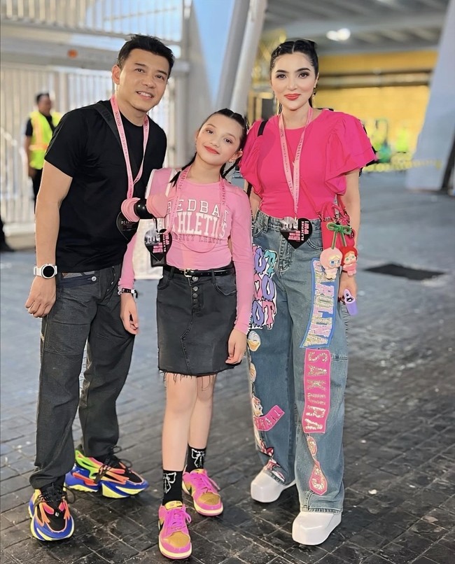 Keluarga Anang Hermansyah ikut euforia konser Blackpink. Ashanty dan putrinya, Arsy tampil dengan gaya pop street style yang penuh warna dan fun. Ashanty mengenakan blouse fuchsia dengan puff sleeve yang dipadukan dengan celana jeans longgar berdesain patchwork dan bordiran warna-warni. Arsy pun tampil segar dengan long sleeve top pink muda yang dipadu rok denim hitam berpotongan mini dan detail unfinished hem. Foto: Dok. Instagram