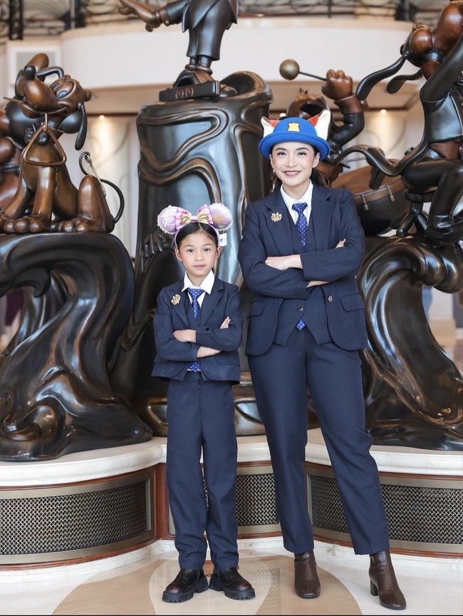 Chelsea Olivia dan Nastusha tampil kompak saat liburan ke Disneyland. Keduanya mengenakan setelan jas biru navy lengkap dengan kemeja putih dan dasi bermotif titik. Chelsea memadukan setelan jasnya dengan sepatu ankle boots cokelat berhak sedang, sementara Nastusha tampil dengan sepatu boots chunky hitam yang memberi kesan bold dan trendi. Foto: Dok. Instagram