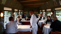 Chef Heinz Beck menyapa penumpang di gerbong makan Orient Express La Dolce Vita saat kereta melaju menuju Montalcino, Italia. Interaksi langsung dengan chef menjadi bagian pengalaman bersantap premium di perjalanan ini. REUTERS/Yara Nardi