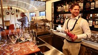 Seorang bartender mengeringkan gelas anggur di bar gerbong lounge kereta Orient Express La Dolce Vita. Area bar menyajikan wine dan minuman eksklusif bagi para pelancong kelas atas. REUTERS/Yara Nardi