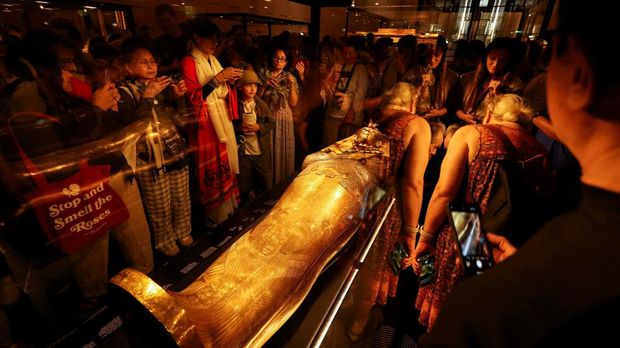 Pengunjung melihat peti mati emas Firaun Mesir kuno Tutankhamun pada hari pertama pengunjung setelah pembukaan resmi Museum Agung Mesir (GEM), dekat kompleks piramida Giza, di Giza, Mesir, 4 November 2025. (REUTERS/Mohamed Abd El Ghany)