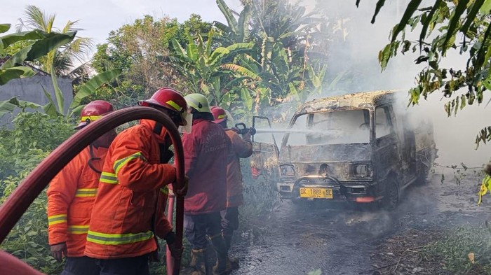 Petugas Damkartan Karangasem melakukan pemadaman kebakaran mobil angkot terbakar di Jalan Ahmad Yani, Kelurahan Subagan, Kamis (6/11/2025). (Dok. Damkartan Karangasem)