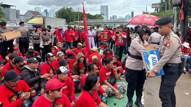 Polwan Polda Metro Jaya turun membagikan air mineral dan roti kepada massa buruh yang demo di DPR, Kamis (6/11/2025).
