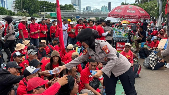 Polwan Polda Metro Jaya turun membagikan air mineral dan roti kepada massa buruh yang demo di DPR, Kamis (6/11/2025).