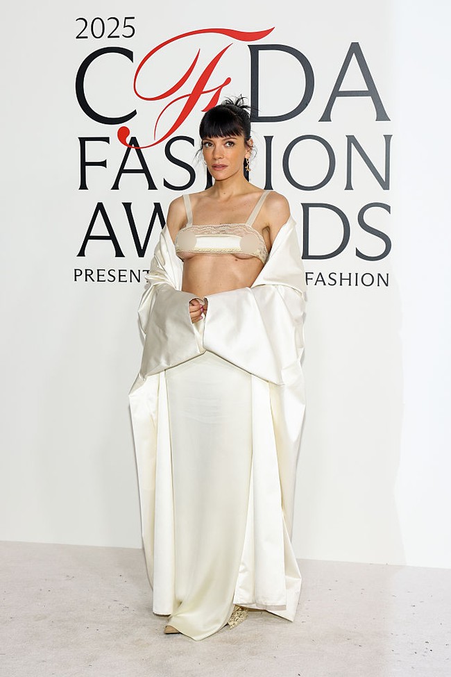 Lily mengenakan busana serba gading rancangan desainer muda Colleen Allen dari koleksi musim semi 2026. Penampilannya terdiri atas bralette renda tipis, rok maxi sutra dengan panel transparan di bagian belakang, serta mantel opera panjang yang dikenakan menjuntai dari bahu. (Foto: Stephanie Augello/WWD via Getty Images)