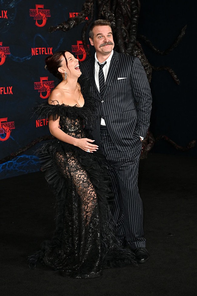 Dalam salah satu momen, David sempat memberikan tatapan ‘nakal’ ke arah kamera, sementara Millie tertawa lepas di sampingnya. Dalam serial populer Netflix tersebut, Millie berperan sebagai Eleven, tokoh utama dengan kekuatan supranatural, sementara David memerankan sosok ayah asuhnya, Kepala Polisi Jim Hopper Jr. Foto: Variety via Getty Images/Michael Buckner