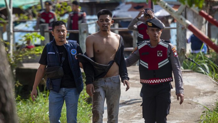 Petugas kepolisian dan Badan Narkotika Nasional (BNN) mengamankan seorang warga yang berusaha kabur saat razia gabungan di Kampung Madani Bersih Narkoba (Bersinar), Muka Kuning, Batam, Kepulauan Riau, Jumat (7/11/2025). Dalam razia gabungan BNNP Kepri bersama Polri, TNI, dan Satpol PP tersebut berhasil mengamankan 36 orang warga yang positif mengkonsumsi narkotika setelah dilakukan tes urine. ANTARA FOTO/Teguh Prihatna/bar