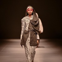 Koleksi ini menampilkan kebaya panjang, baju kurung berpeplum, serta tailoring bernuansa militer yang dikombinasikan dengan material daur ulang dan pewarnaan tangan, menciptakan tafsir baru tentang kekuatan. Beberapa di antaranya hadir dengan bawahan rok berdraperi seperti sarung yang menjuntai. Foto: Dok. JFW
