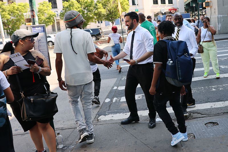 Gaya Zohran Mamdani, Muslim Pertama Jadi Wali Kota New York NEW YORK, NEW YORK - JUNE 24: New York mayoral candidate, State Rep. Zohran Mamdani (D-NY) greets voters with Democratic mayoral candidate Michael Blake on 161st Street on June 24, 2025 in the South Bronx in New York City. Mamdani held several campaign events throughout the day including greeting voters with mayoral candidates Blake and NYC Comptroller and Mayoral Candidate Brad Lander as voters in NYC vote for the democratic nominee for mayor to replace Mayor Eric Adams. (Photo by Michael M. Santiago/Getty Images)