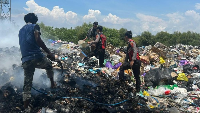 Tim Polsek Penida bergotong royong bersama warga memadamkan api yang muncul di gudang, dekat TPA Jungutbatu.