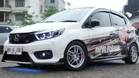 Mobil modif Honda terbaik asal Palembang jatuh pada Honda Brio Community. Honda Brio dari Palembang ini tampil penuh energi dengan sentuhan modifikasi eksterior seperti headlamp double biled, foglamp biled, stoplamp RGB, hingga lampu kolong RGB yang menegaskan karakter street-modded. Foto: dok. Honda Prospect Motor