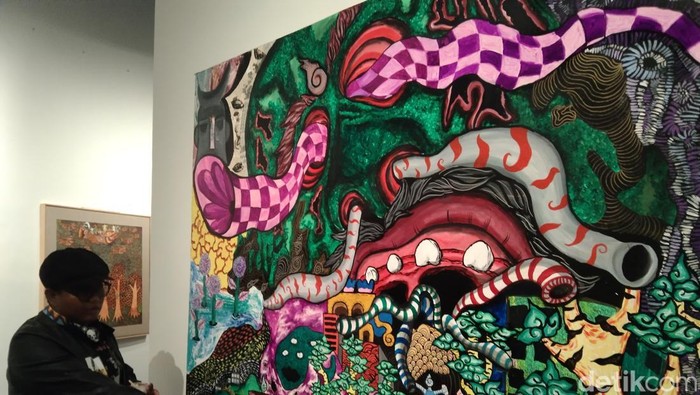 Muhammad Kholilullah (kiri) saat menjelaskan lukisannya bernama Aku Sayang Bali kepada pengunjung di Labyrinth Art Gallery di Nuanu Creative City, Sabtu (8/11/2025). /Krisna Pradipta