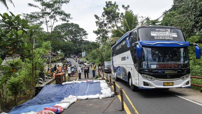 Pekerja menutup material tanah longsor menggunakan terpal di Jembatan Cikaleho, Kecamatan Cipaku, Kabupaten Ciamis, Jawa Barat, Sabtu (8/11/2025). Jalan nasional penghubung Ciamis–Cirebon atau jalur menuju Tol Cipali amblas akibat hujan deras yang mengguyur wilayah tersebut pada Jumat (7/11), sehingga arus lalu lintas diberlakukan sistem buka-tutup. ANTARA FOTO/Adeng Bustomi/rwa.