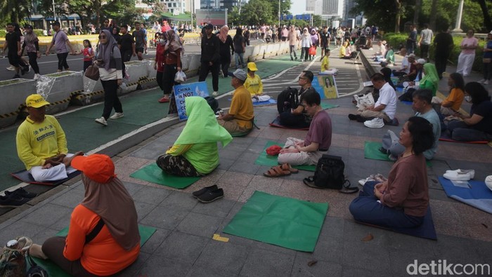 Peserta Falun Dafa memusatkan pikiran sambil melakukan gerakan meditasi lembut saat Car Free Day di kawasan Dukuh Atas, Jakarta, Minggu (9/11/2025).
