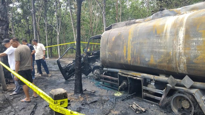 Polisi memasangkan garis polisi bekas tempat terbakar truck tangki.