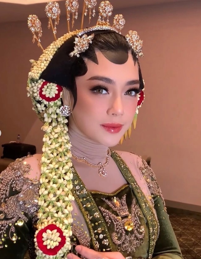 Celine tampil dengan riasan paes khas pengantin Jawa yang dibuat rapi di dahi Meski identik dengan tampilan pengantin tradisional, makeup-nya terlihat modern dengan sentuhan highlighter lembut dan lip gloss berwarna pink natural yang membuat wajahnya tampak segar. Foto: Instagram/@hepidavid