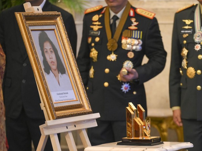 Adik aktivis buruh Marsinah, Wijiyati menangis di balik foto kakaknya usai mengikuti upacara pemberian gelar pahlawan kepada Marsinah dan sembilan tokoh lainnya di Istana Negara, Jakarta, Senin (10/11/2025). Presiden Prabowo menganugerahkan gelar Pahlawan Nasional kepada 10 tokoh yang dinilai berjasa besar bagi Indonesia, antara lain K.H. Abdurrahman Wahid, Jenderal Besar TNI H.M. Soeharto, Marsinah, Mochtar Kusumaatmaja, Hj. Rahma El Yunusiyyah, Jenderal TNI (Purn) Sarwo Edhie Wibowo,  Sultan Muhammad Salahuddin, Syaikhona Muhammad Kholil, Tuan Rondahaim Saragih, dan Zainal Abidin Syah. ANTARA FOTO/Aditya Pradana Putra