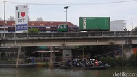 Sejumlah pengendara sepeda motor menggunakan perahu eretan menyeberangi Sungai Kali Cagak di Kecamatan Penjaringan, Jakarta, Senin (10/11/2025).