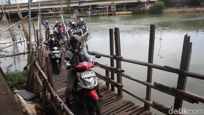 Sejumlah pengendara sepeda motor menggunakan perahu eretan menyeberangi Sungai Kali Cagak di Kecamatan Penjaringan, Jakarta, Senin (10/11/2025). Warga memanfaatkan jasa penyeberangan perahu eretan untuk memangkas jarak hingga 7 km dengan mengurangi waktu tempuh pada jam macet mencapai 30 menit. Setiap pengendara dikutip tarif Rp 2.000 untuk sekali jalan.  Perahu eretan ini menghubungkan Kapuk Muara di sisi barat dengan Muara Karang hingga Pluit di sisi timur.  Perahu tersebut beroperasi sejak pukul 03.00 WIB hingga 22.00 WIB.